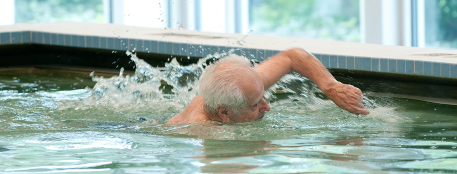 Active senior enjoying a swim in the pool at Acacia Village