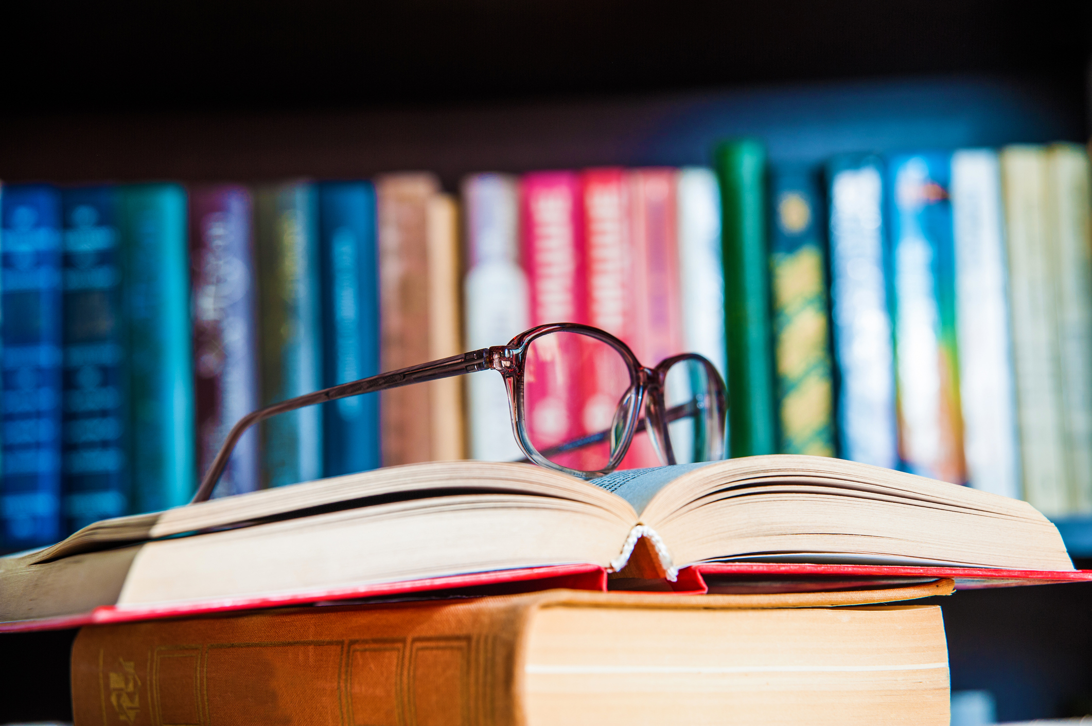 Bookshelf, open book with reading glasses on it.