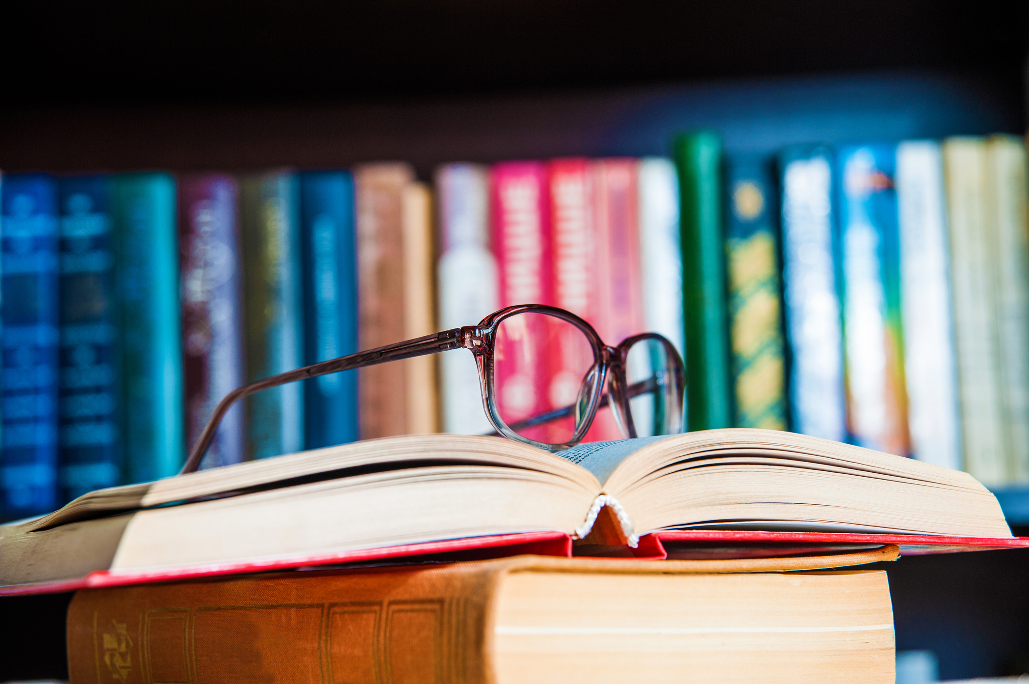 Bookshelf, open book with reading glasses on it.